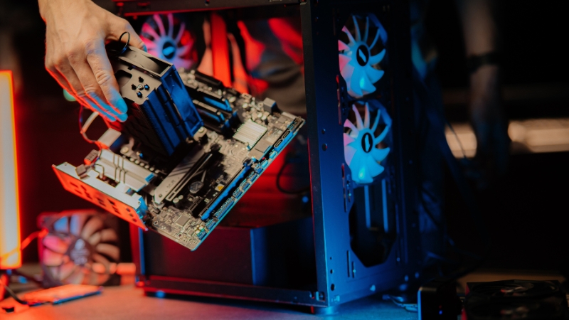 Osoba drži matičnu ploču sa montiranim hladnjakom pored otvorenog kućišta