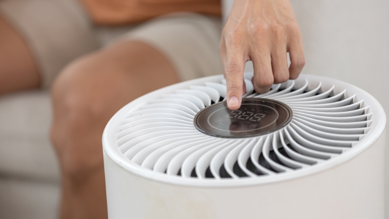 Ruka podešava nivo vlažnosti na uređaju za regulaciju vazduha u dnevnoj sobi