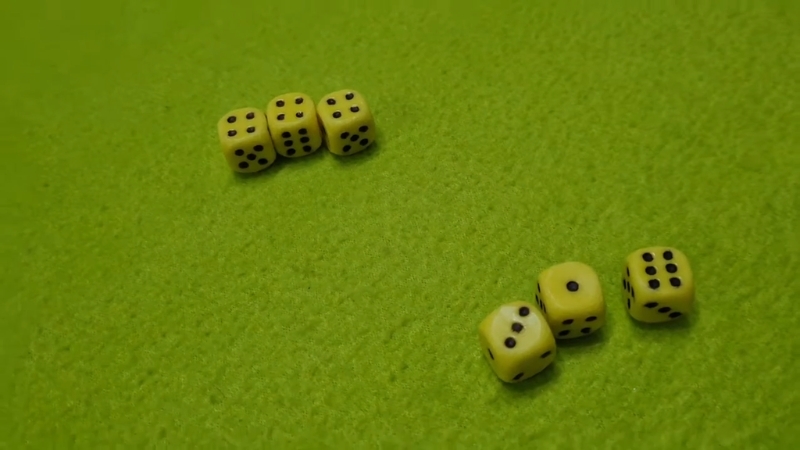 Žute kockice bačene na zelenoj podlozi, raspoređene u dve grupe tokom igre jamb