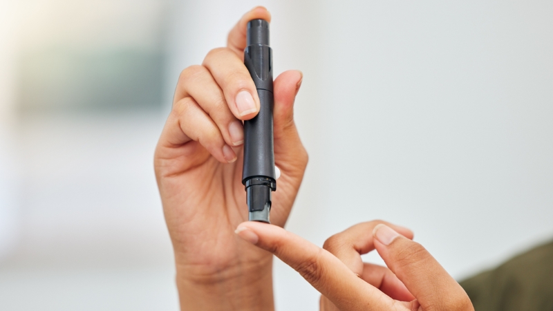 Osoba proverava nivo šećera u krvi pomoću aparata za merenje glukoze ubodom u prst